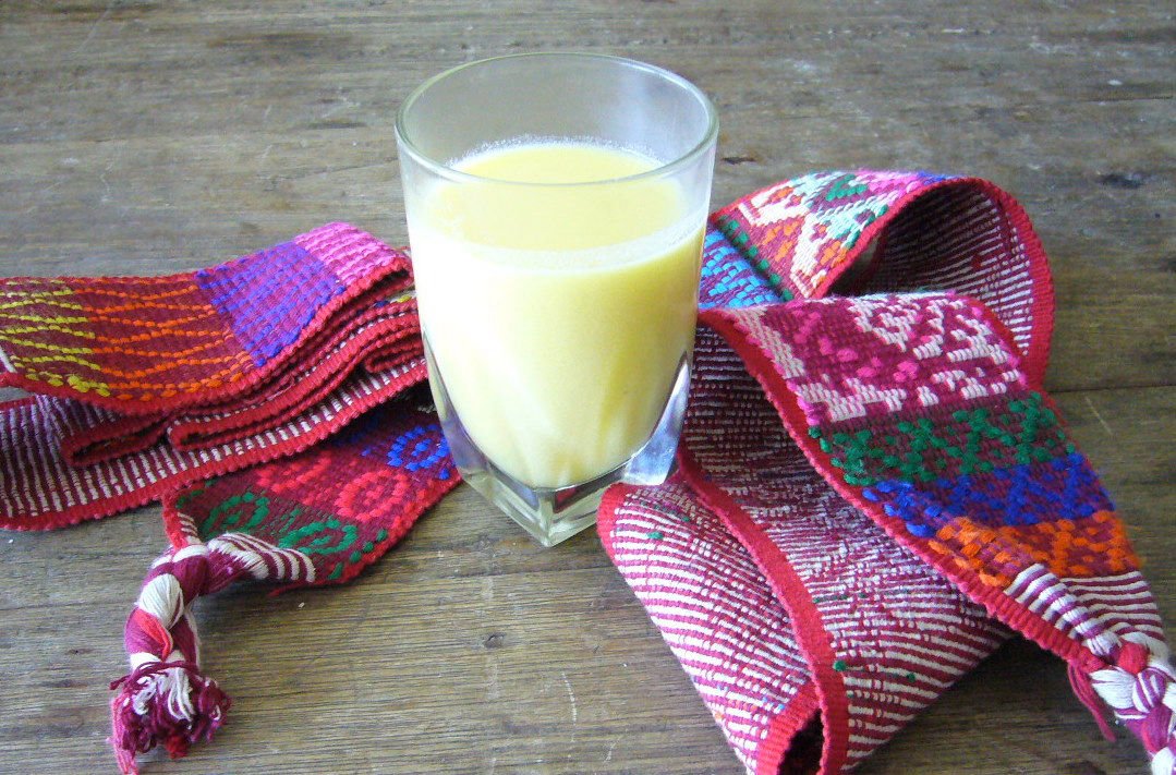 Vaso de atol de elote sobre una faja tejida