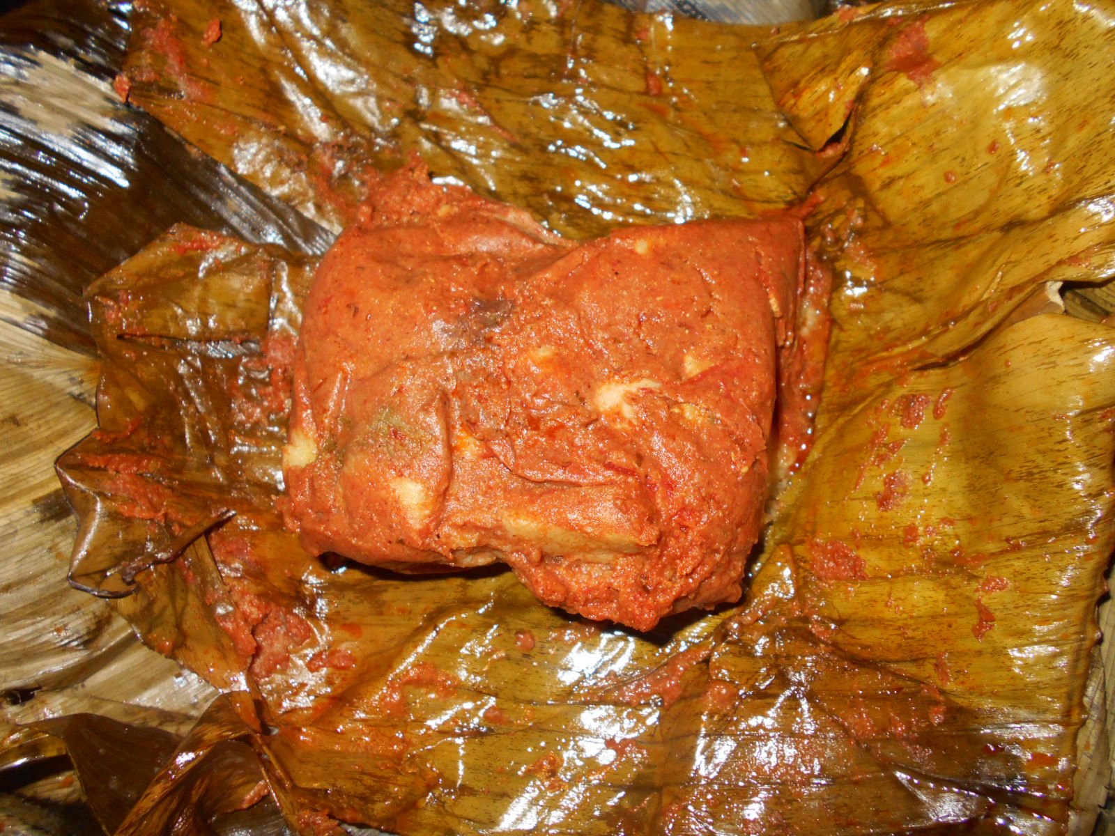 Tamal colorado abierto sobre su hoja